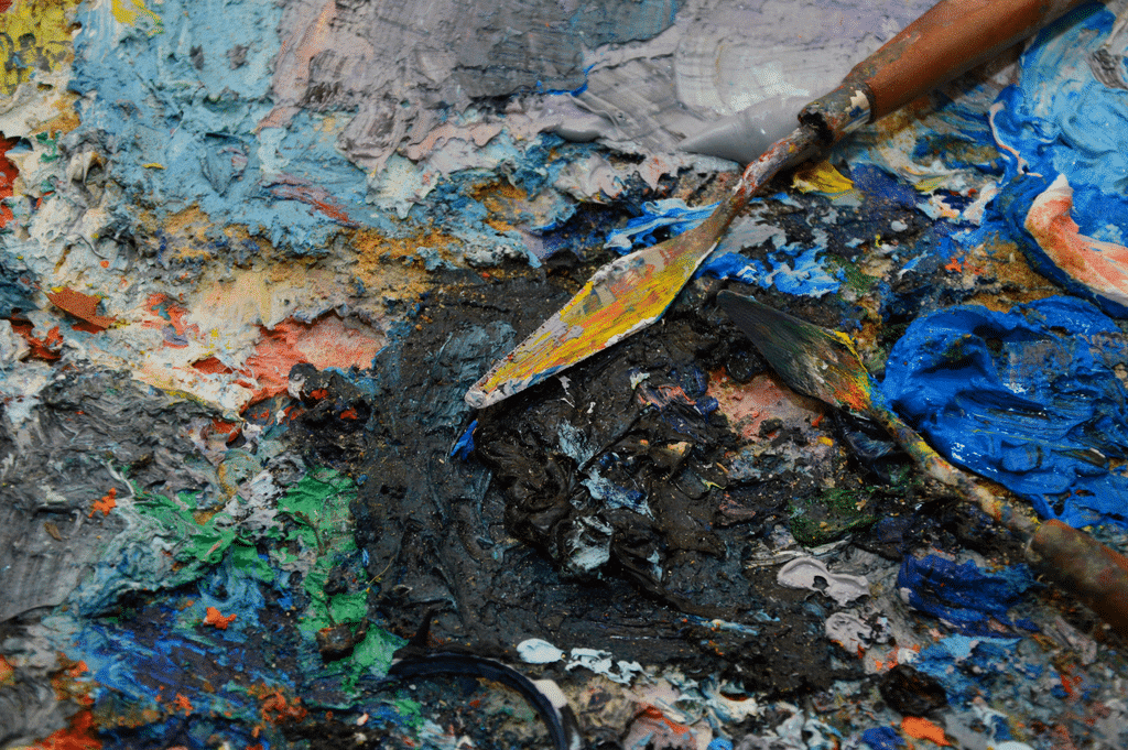 Couteaux de palette sur palette texturée, peintures à l'huile mélangées vibrantes.