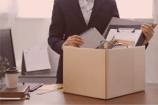 Collaborateur range ses affaires dans un carton, symbolisant un départ professionnel en entreprise.